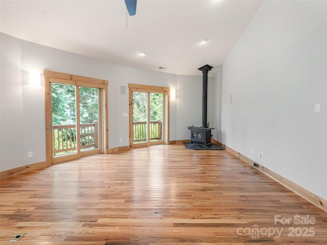 15 Sassy Ln, Asheville, NC 28805 - unfurnished living room featuring a wood stove, light wood finished floors, baseboards, and a ceiling fan