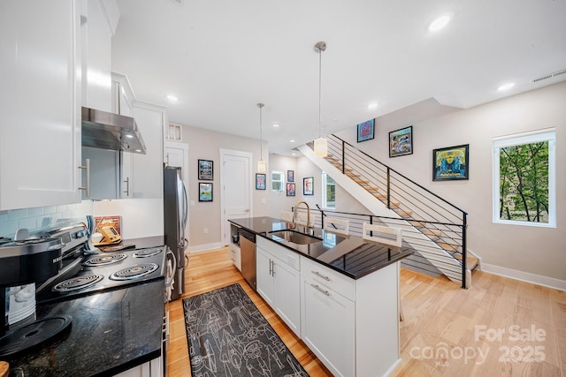 1115 Greenleaf Ave Unit B, Charlotte, NC 28202 - kitchen with wall chimney range hood, appliances with stainless steel finishes, a sink, white cabinets, and light wood-style floors