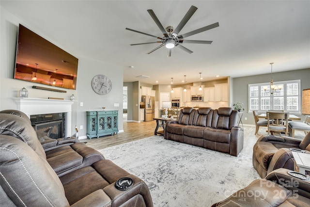 4083 Home Grown Way, Clover, SC 29710 - living room with ceiling fan with notable chandelier, a glass covered fireplace, light wood-style flooring, and baseboards