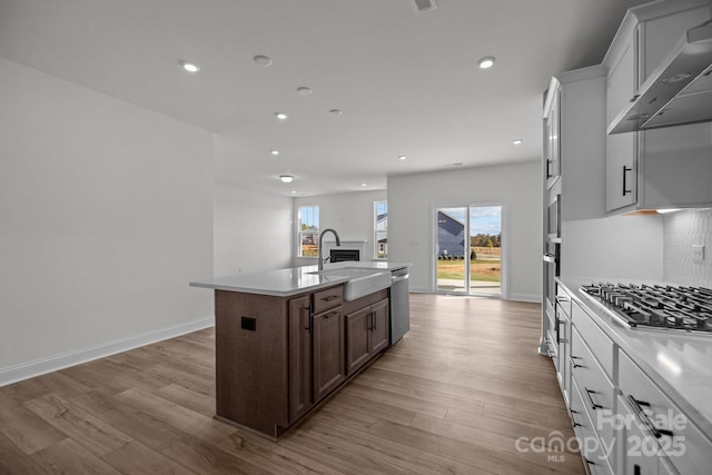 124 Canary Ln Unit 7, Mooresville, NC 28115 - kitchen with a sink, appliances with stainless steel finishes, an island with sink, light wood finished floors, and wall chimney range hood