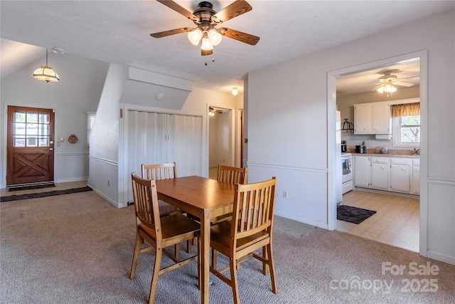 dining room featuring ceiling fan, light carpet, and baseboards