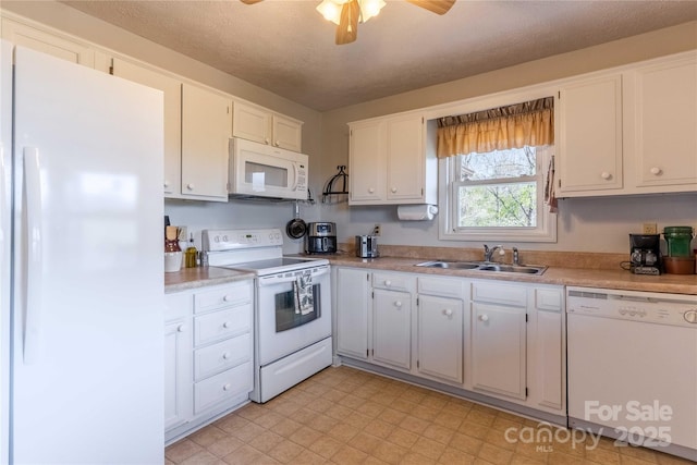 kitchen with white appliances, a sink, white cabinetry, light countertops, and ceiling fan