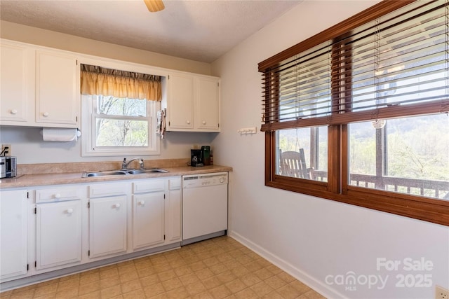 kitchen featuring white dishwasher, a sink, baseboards, white cabinetry, and light countertops