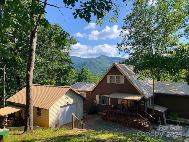 rear view of house with an attached garage, metal roof, a mountain view, and an outdoor structure
