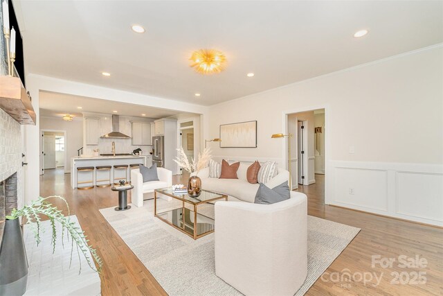 426 Walden Trl, Waxhaw, NC 28173 - living room featuring ornamental molding, wainscoting, a brick fireplace, recessed lighting, and light wood finished floors