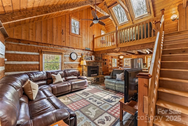 living area with stairway, wood walls, wooden ceiling, high vaulted ceiling, and ceiling fan