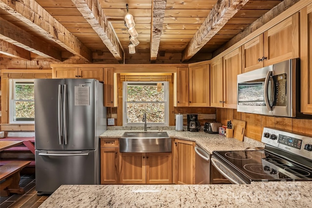kitchen with a sink, beamed ceiling, wood ceiling, light stone countertops, and appliances with stainless steel finishes