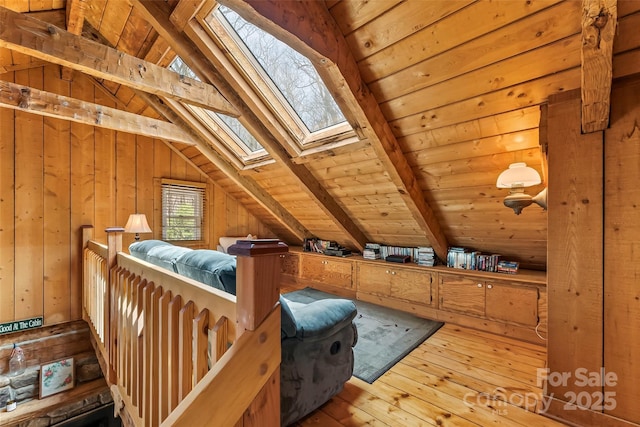 interior space featuring hardwood / wood-style flooring, lofted ceiling with skylight, and wooden walls