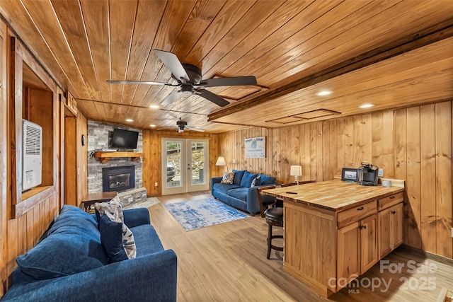 living room with wood ceiling, a stone fireplace, and wood walls