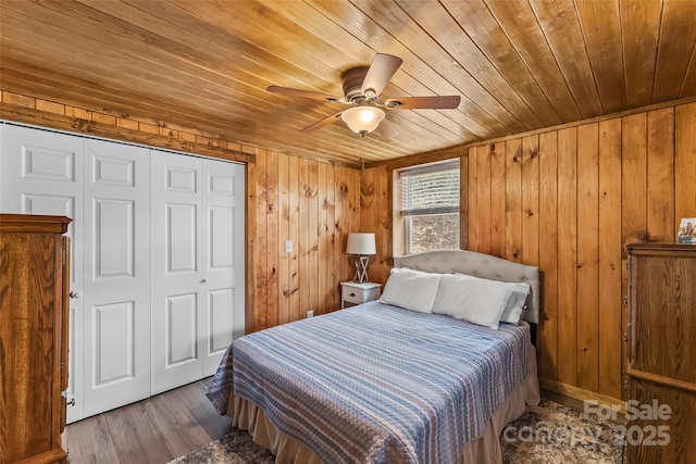 bedroom with wooden walls, wood finished floors, a closet, and wooden ceiling
