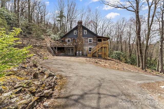 view of front of property with a wooden deck, french doors, driveway, and stairway