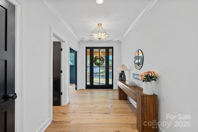 doorway with baseboards, crown molding, and light wood-style floors