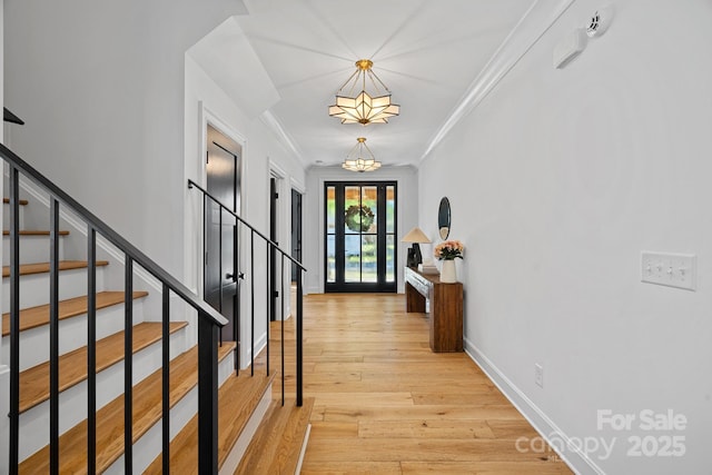 entrance foyer with baseboards, crown molding, stairs, and light wood-style floors