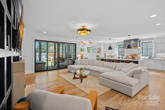 living room featuring light wood finished floors, french doors, recessed lighting, and a healthy amount of sunlight