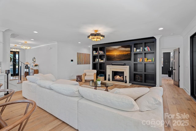 living area with an inviting chandelier, recessed lighting, a lit fireplace, and crown molding