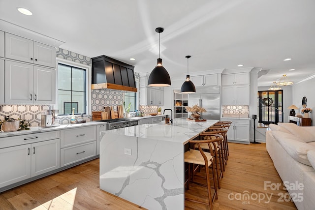 kitchen featuring built in fridge, premium range hood, recessed lighting, and tasteful backsplash
