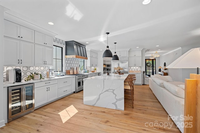kitchen with recessed lighting, high end appliances, wine cooler, backsplash, and a breakfast bar area