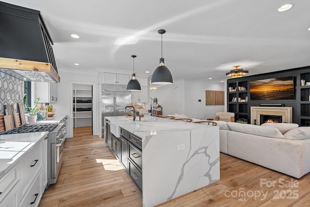 kitchen with wall chimney exhaust hood, recessed lighting, light stone counters, crown molding, and high quality appliances