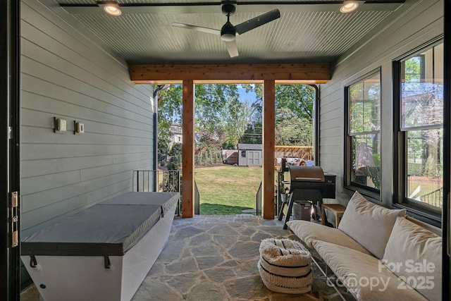 sunroom with wooden walls, ceiling fan, and a healthy amount of sunlight