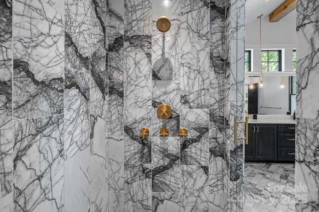 full bathroom with beamed ceiling, vanity, and a marble finish shower