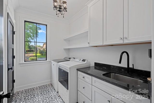 washroom with a sink, separate washer and dryer, a chandelier, cabinet space, and baseboards