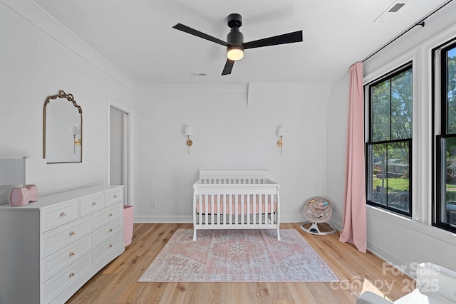 bedroom featuring light wood-style flooring, visible vents, and a crib