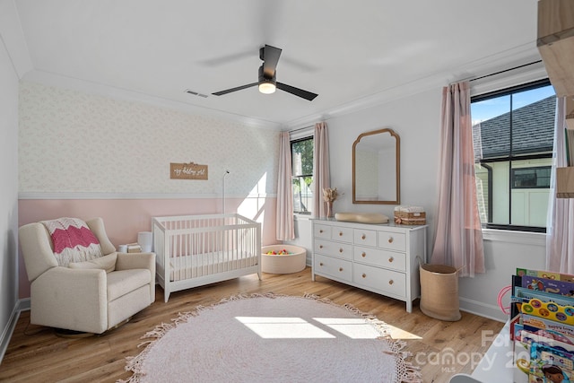 bedroom featuring a wainscoted wall, light wood-style floors, and wallpapered walls