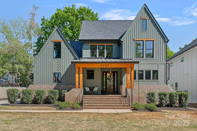 modern inspired farmhouse with board and batten siding, a shingled roof, covered porch, brick siding, and a standing seam roof