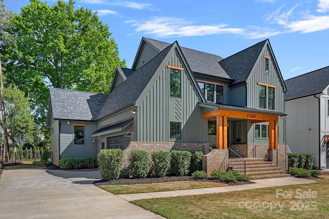 view of front of house with board and batten siding, a shingled roof, driveway, and a garage