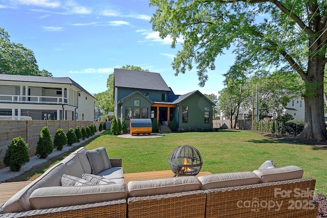 back of property featuring a lawn, a fenced backyard, and an outdoor living space with a fire pit