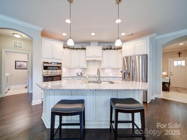 kitchen featuring washing machine and clothes dryer, a sink, arched walkways, stainless steel appliances, and visible vents