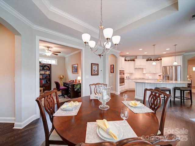 dining area featuring arched walkways, dark wood-style flooring, baseboards, a ceiling fan, and crown molding