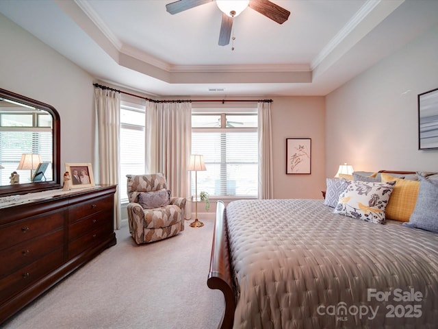 carpeted bedroom with a raised ceiling, ceiling fan, multiple windows, and ornamental molding