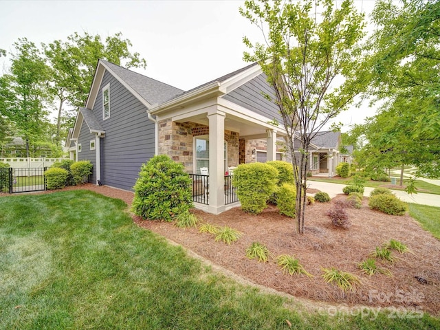 view of property exterior featuring fence, a lawn, covered porch, and stone siding