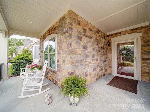 doorway to property featuring stone siding and covered porch
