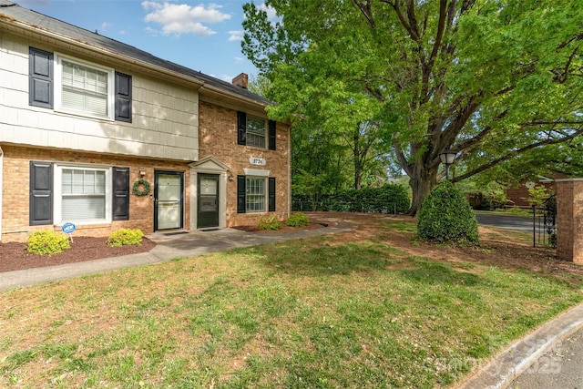 exterior space with a chimney, brick siding, and a front yard