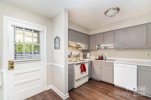 kitchen featuring a sink, white appliances, dark wood finished floors, under cabinet range hood, and gray cabinetry