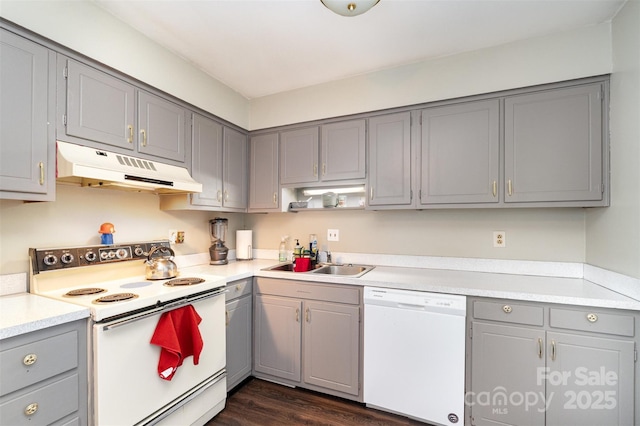 kitchen with a sink, white appliances, light countertops, under cabinet range hood, and gray cabinetry