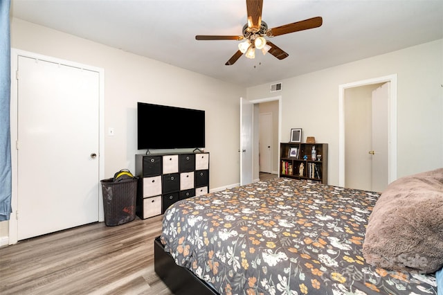 bedroom with ceiling fan, wood finished floors, and visible vents