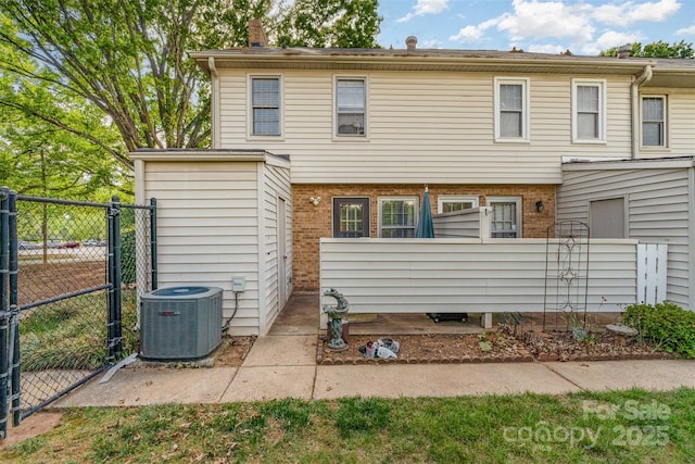 exterior space with fence, brick siding, a gate, and central AC unit