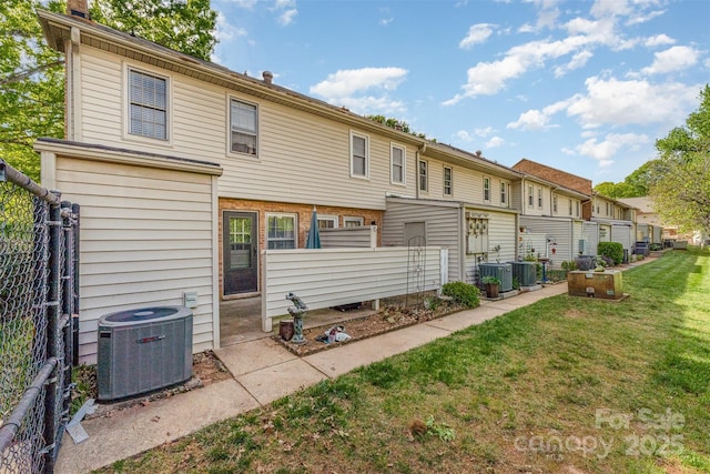 back of house featuring fence, a residential view, a yard, and central air condition unit
