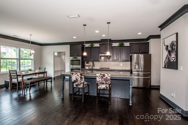 10707 Charmont Pl, Huntersville, NC 28078 - kitchen with appliances with stainless steel finishes, ornamental molding, backsplash, a center island with sink, and light stone counters