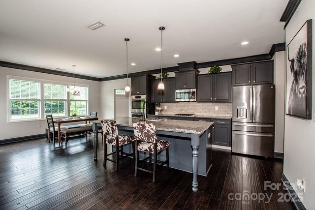 10707 Charmont Pl, Huntersville, NC 28078 - kitchen featuring stainless steel appliances, crown molding, a kitchen island with sink, a chandelier, and a kitchen bar