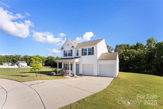 view of front of property with covered porch, an attached garage, a front yard, and concrete driveway