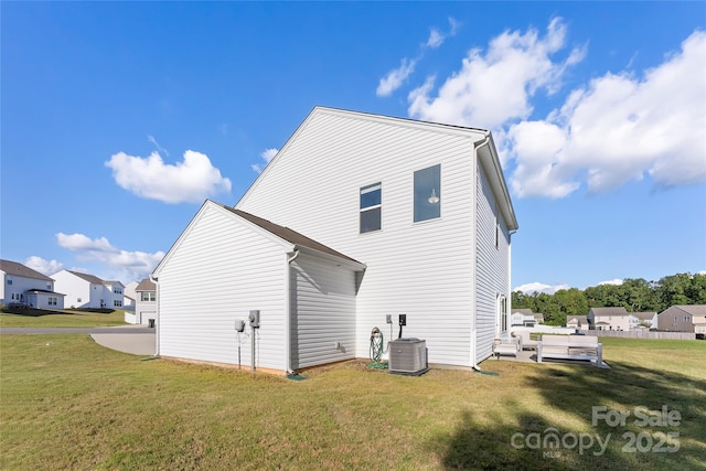 back of house featuring cooling unit, a residential view, and a lawn