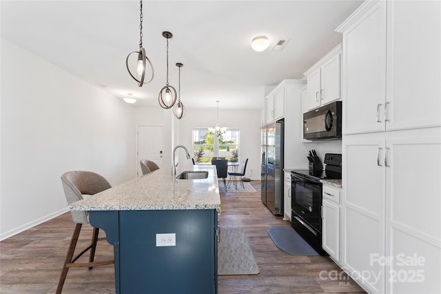 548 Dutch White Dr, Clover, SC 29710 - kitchen with black appliances, a sink, a breakfast bar, a center island with sink, and white cabinetry