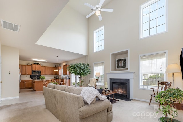 living room with visible vents, baseboards, a high ceiling, and light carpet