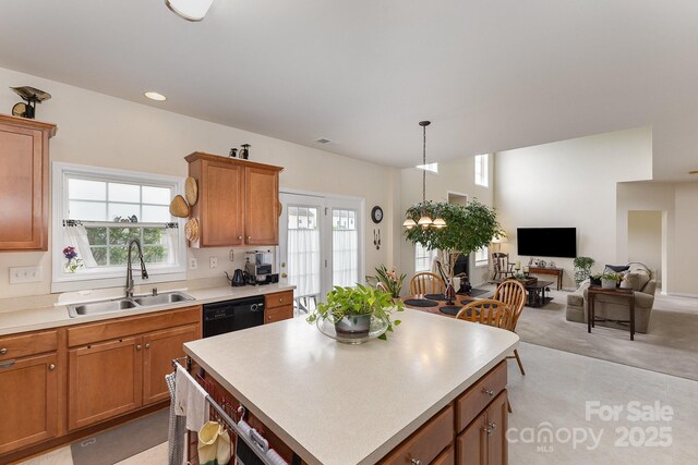 kitchen featuring a center island, brown cabinets, dishwasher, a sink, and light countertops