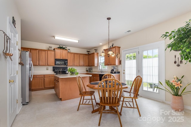 kitchen with brown cabinetry, a kitchen island, visible vents, light countertops, and black appliances
