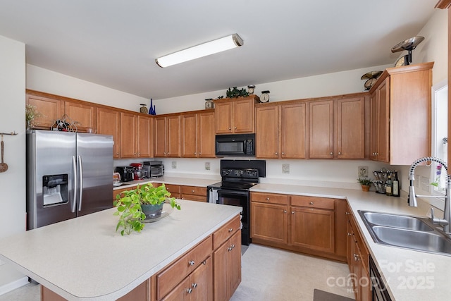 kitchen with brown cabinets, a sink, light countertops, a center island, and black appliances